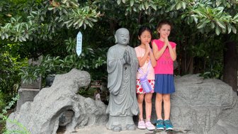 Kinder posieren neben traditionellen Statuen vor der Großen Wildganspagode in Xi’an – China Reise mit Kindern