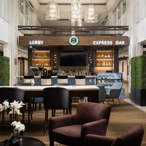 Der elegante Empfangsbereich des Holiday Inn in Toronto zeigt eine stilvolle Bar mit modernen Möbeln und Pflanzen.