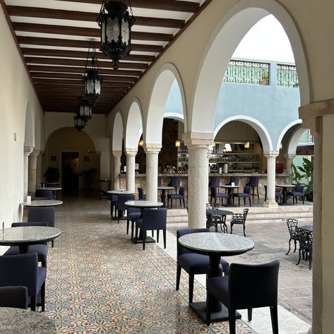 Ein stilvolles Restaurant mit eleganten runden Tischen, von Bögen und hängenden Laternen umgeben.