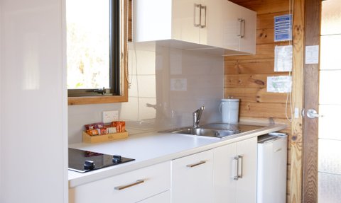 Eine moderne Küche mit weißen Schränken, einem Waschbecken und einem Herd, umgeben von Holzverkleidung.