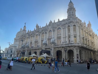 Die beeindruckende Architektur eines historischen Gebäudes in der Stadt, umgeben von Menschen und bunten Taxis.