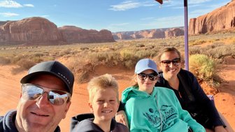 Eine Familie genießt eine Jeep-Tour durch die beeindruckende Landschaft von Monument Valley, umgeben von roten Felsen.