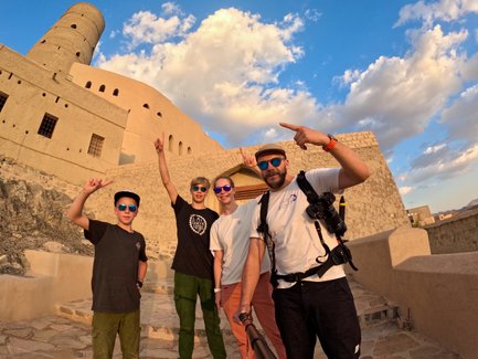 Familie macht Selfie mit Gebäude vom Bahla Fort im Oman – Oman Reise mit Kindern