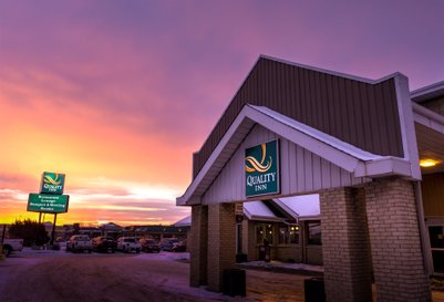 Die Fassade des Quality Inn in Edmonton wird von einem beeindruckenden Sonnenuntergang in lila und orange beleuchtet.