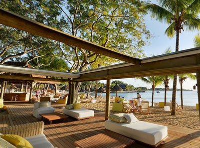 Ein entspannender Strandbereich mit Liegen und Palmen, der eine ruhige Atmosphäre am Wasser vermittelt.