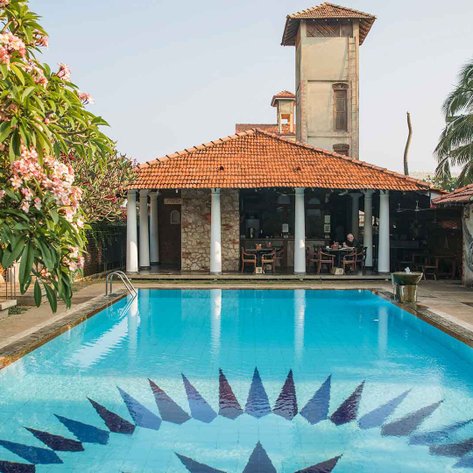 Ein einladender Pool mit blauen Fliesen und einem auffälligen Muster, umgeben von üppigem Grün und blühenden Bäumen.