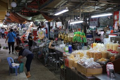 Ein belebter Markt in Ho-Chi-Minh-Stadt mit Ständen voller Lebensmittel und Menschen, die einkaufen und arbeiten.