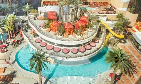 Ein lebhafter Poolbereich mit Palmen, bunten Liegen und einem aufregenden Wasserrutschen, ideal für Entspannung und Spaß.