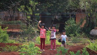 Lächelnde Kinder winken Besuchern in einem thailändischen Dorf – Thailand Reise mit Kindern