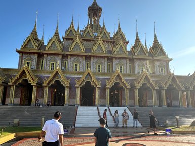 Zwei Männer gehen auf den Eingang des prächtigen Wat Chantharam Kristalltempels in Uthai Thani zu - Thailand Familienreise