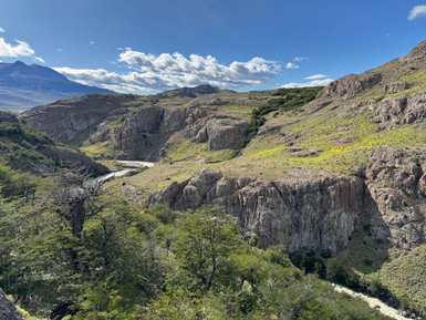 Eine beeindruckende Landschaft mit steilen Felsen und üppigem Grün, durchzogen von einem schmalen Fluss im Tal.
