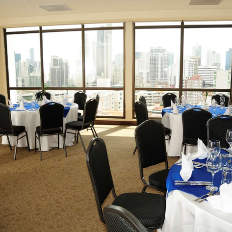 Ein eleganter Restaurantbereich mit runden Tischen, dekoriert mit blauen Tischdecken und Blick auf die Stadt.