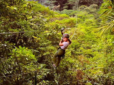 Mädchen gleitet lachend an einer Zipline durch den Dschungel bei einer Canopy-Tour – Costa Rica Familienreise