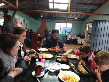 Eine Gruppe von Menschen sitzt an einem Tisch und genießt ein herzhaftes Essen in einem rustikalen Restaurant.
