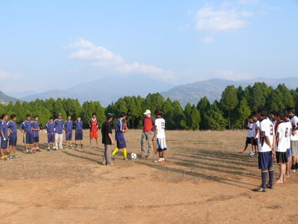 Eine Gruppe von Jugendlichen steht auf einem Fußballfeld, während ein Trainer Anweisungen gibt und ein Ball bereitliegt.