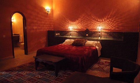 Ein gemütliches Hotelzimmer mit einem großen roten Bett, sanfter Beleuchtung und einem warmen, einladenden Ambiente.