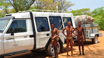 Einheimische stehen direkt neben einem Jeep in der Sonne - Namibia mit Kindern