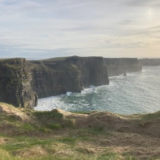 Die Klippen von Moher erheben sich majestätisch über dem tosenden Atlantik, umgeben von sanften grünen Hügeln.
