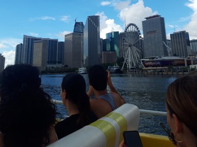Die Skyline von Miami wird von einem Boot aus betrachtet, während Menschen am Rand des Bootes sitzen und die Aussicht genießen.
