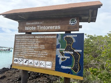 Ein Willkommensschild für Islo Tintoreras in den Galapagos, mit Informationen über den Wanderweg und die Umgebung.