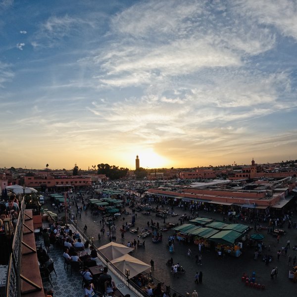 Der belebte Djemaa el Fna Platz in warmes Abendlicht getaucht bei Sonnenuntergang – Marokko mit Kindern