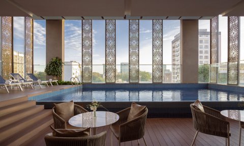 Ein eleganter Innenpool mit blauen Fliesen, umgeben von großen Fenstern und modernen Liegen, die zum Entspannen einladen.