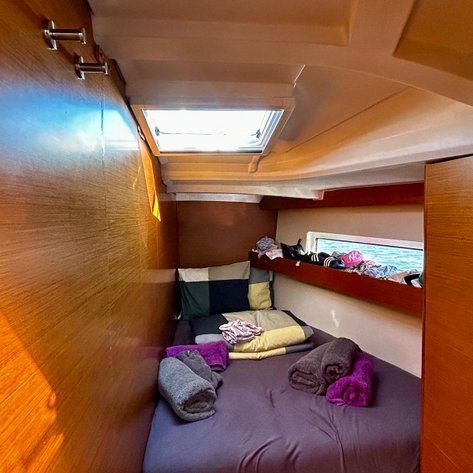 Ein gemütlicher Schlafbereich auf einem Boot, ausgestattet mit bunten Kissen und frisch gefalteten Handtüchern.