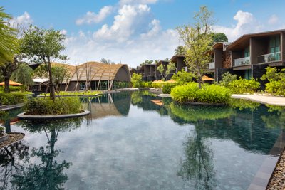 Ein ruhiger Poolbereich umgeben von üppigem Grün und modernen Gebäuden, ideal für Entspannung und Erholung.