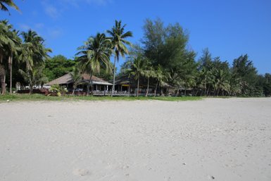 Blick von einem Strand in Chumphon auf eine Hütte, die von Palmen umgeben ist - Thailand mit Kindern