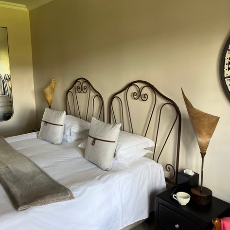 Ein stilvolles Schlafzimmer mit zwei Betten, eleganten Kopfenden und dekorativen Kissen, die eine gemütliche Atmosphäre schaffen.