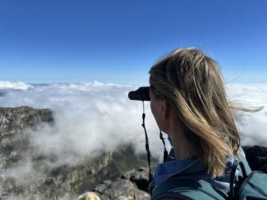 Mutter beobachtet die Aussicht mit Fernglas auf dem Tafelberg – Südafrika Familienreise