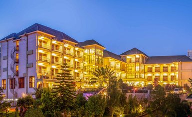 Das Nyaika Hotel erstrahlt in warmem Licht, umgeben von üppigem Grün und einem klaren Abendhimmel.