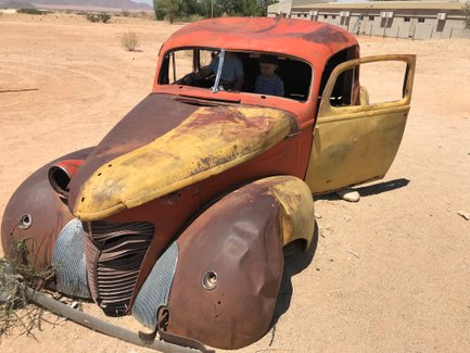 Ein rostiges Auto steht verlassen in der Wüste - Namibia mit Kindern