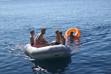 Eine Gruppe von Kindern und einem Erwachsenen fährt in einem Gummiboot auf dem ruhigen blauen Wasser des Meeres.