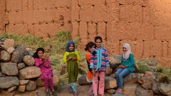 Fröhliche einheimische Kinder mit strahlenden Gesichtern in einem marokkanischen Dorf – Marokko Familienreise