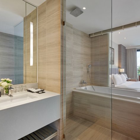 Ein modernes Badezimmer mit einer eleganten Badewanne und einem Waschbecken, umgeben von stilvollen Fliesen und Spiegeln.