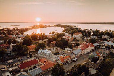 Die malerische Stadt Haapsalu wird von der untergehenden Sonne in warmen Farben beleuchtet, während das Wasser sanft glitzert.