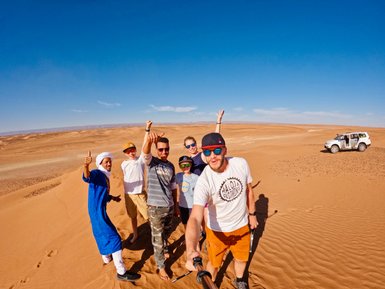 Familie posiert fröhlich für ein Selfie mit Guides in der weiten Sahara – Marokko mit Kindern
