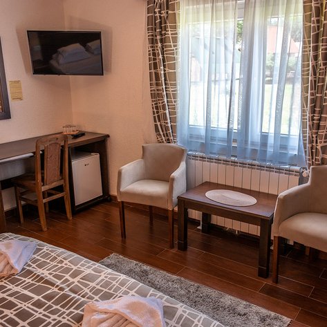 Ein gemütliches Zimmer mit einem Doppelbett, einem Schreibtisch und zwei bequemen Stühlen, ideal für Entspannung.