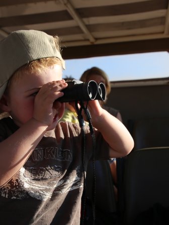 Kind beobachtet mit einem Fernglas während einer Safari – Südafrika Reise mit Kindern