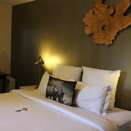 Ein gemütliches Schlafzimmer mit einem großen Bett, dekoriert mit Kissen und einem kleinen Blumenarrangement auf der Bettdecke.