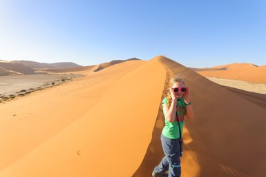 Ein Kind läuft eine Düne hinauf - Namibia Urlaub mit Kindern
