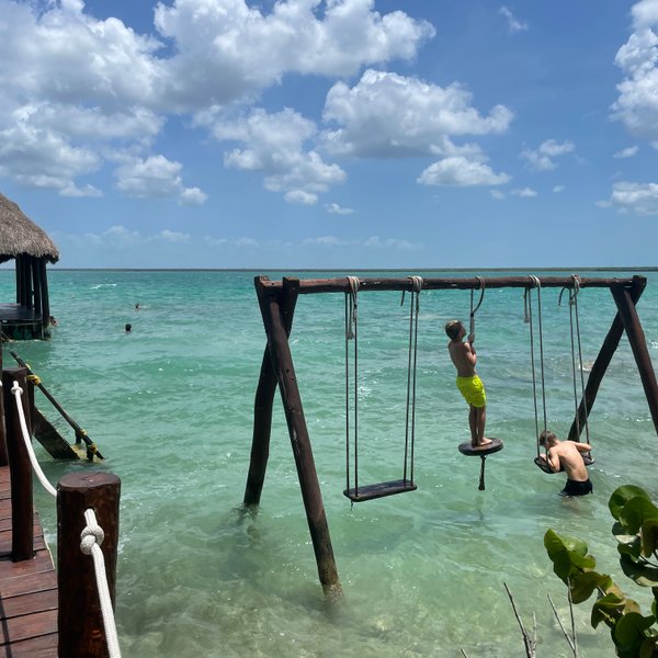 Kinder schaukeln auf einer Wasserschaukel in der Lagune von Bacalar – Mexiko Familienreise