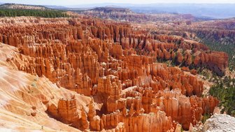 Die beeindruckenden, orangefarbenen Felsformationen des Bryce Canyon erstrecken sich unter einem klaren blauen Himmel.
