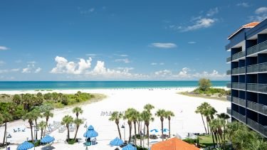 Ein atemberaubender Blick auf den weißen Sandstrand und das türkisfarbene Wasser unter einem strahlend blauen Himmel.