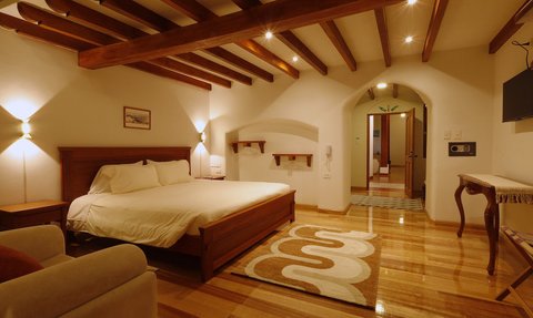 Ein gemütliches Hotelzimmer mit einem großen Bett, warmem Licht und Holzbalken an der Decke, das eine einladende Atmosphäre schafft.