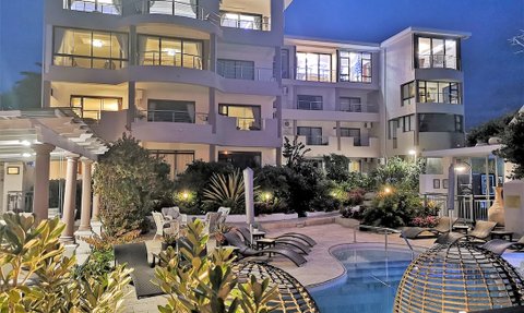 Ein elegantes Boutique-Hotel mit einem einladenden Poolbereich, umgeben von üppigem Grün und stilvollen Liegen.