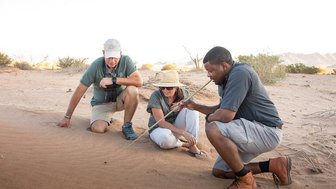 Guide erklärt zwei Reisenden die Tierwelt der Wüste - Namibia mit Kindern
