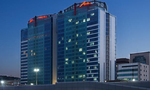 Das Asti Hotel in Busan erstrahlt in der Dämmerung, mit leuchtenden Fenstern und einem modernen Glasdesign.