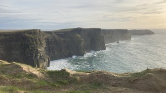 Die Klippen von Moher erheben sich majestätisch über dem tosenden Atlantik, umgeben von sanften grünen Hügeln.